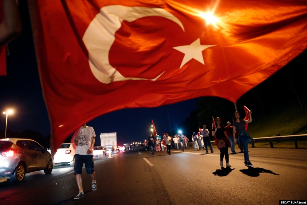 Mbështetësit e Erdoganit duke mbajtur një flamur të madh turk në Urën e Bosforit më 21 korrik 2016. Kryeministri Binali Yıldırım njoftoi se ura do të riemërohej Ura e Martirëve të 15 Korrikut për nder të civilëve që vdiqën duke i rezistuar përpjekjes për grushtshtetin.