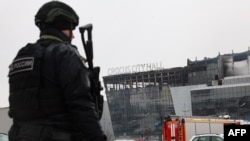 Сотрудник российских правоохранительных органов патрулирует территорию у концертного зала «Крокус Сити Холл» в подмосковном Красногорске, 23 марта 2024 года