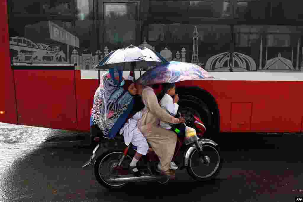 O familie se plimbă pe bicicletă în timpul ploilor musonice din Lahore, Pakistan.