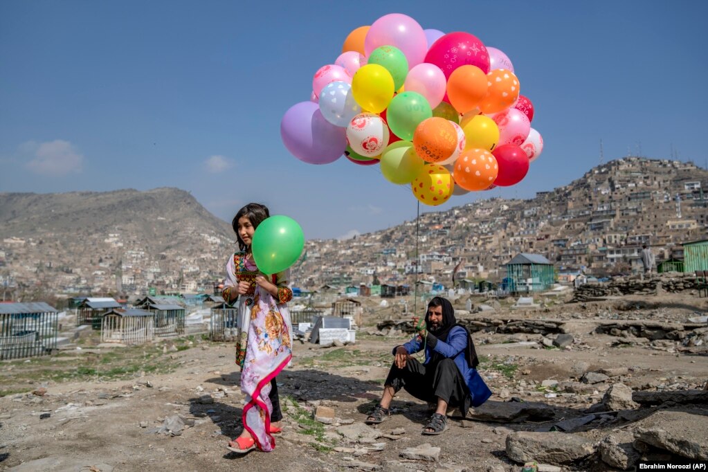 A girl buys a balloon for the Norouz celebration from a vendor at a cemetery in Kabul. The Taliban canceled the public holiday, though the militants have insisted those who wish to celebrate will not be prevented from doing so.