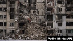 Un grup de femei trece pe lângă o clădire avariată de bombardamentele rusești în cartierul Saltivka din Harkov, Ucraina, joi, 16 februarie 2023