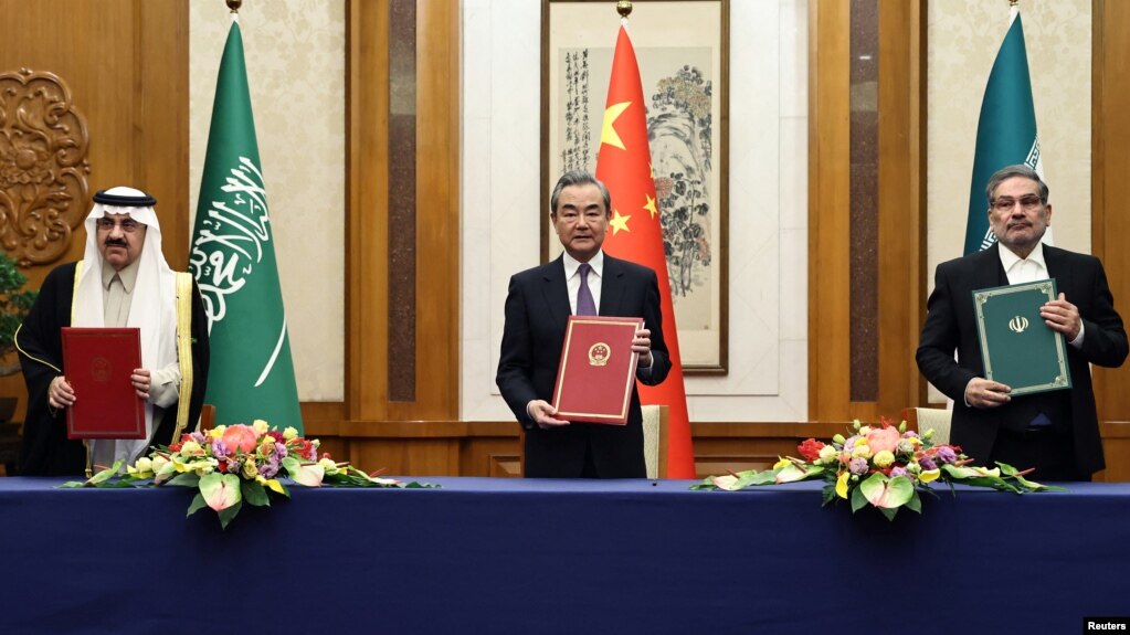 Top Chinese diplomat Wang Yi holds up a March 10 deal in Beijing with Secretary of Iran's Supreme National Security Council Ali Shamkhani and Saudi State Minister Musaad bin Muhammad al-Aiban.