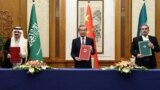 Top Chinese diplomat Wang Yi holds up a March 10 deal in Beijing with Secretary of Iran's Supreme National Security Council Ali Shamkhani and Saudi State Minister Musaad bin Muhammad al-Aiban.