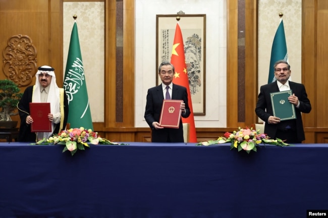 Wang Yi holds up a March 2023 deal in Beijing with Iranian Supreme National Security Council Secretary Ali Shamkhani (right) and Saudi State Minister Musaad bin Muhammad al-Aiban (left).