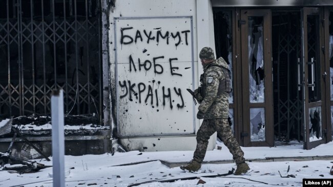 Украинский военнослужащий в центре Бахмута Донецкой области, 12 февраля 2023 года. Надпись на стене: "Бахмут любит Украину"