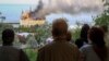 Люди дивляться на палаючу будівлю навчального закладу після російського ракетного удару по Одесі. Україна, 29 квітня 2024 року