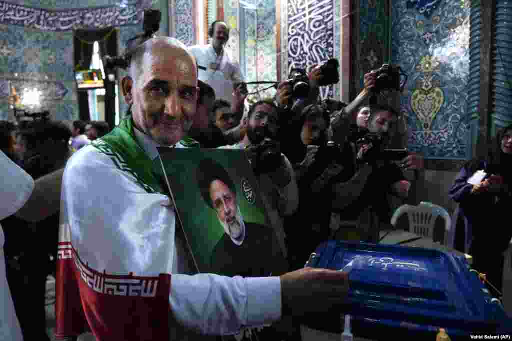 Muškarac ubacuje listić u kutiju dok drži portret Raisija. Raisi, kojeg mnogi Iranci nazivaju &quot;teheranskim mesarom&quot; zbog njegove navodne uloge u masovnom pogubljenju političkih zatvorenika 1988. godine dok je bio zamjenik teheranskog tužitelja, poginuo je s ministrom vanjskih poslova Hosseinom Amir-Abdollahianom i nekoliko drugih dužnosnika u padu helikoptera 19. maja.