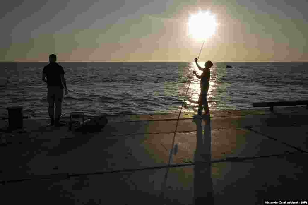 A fisherman prepares his fishing rod during sunset on a beach in the Russian Black Sea resort of Sochi.&nbsp;