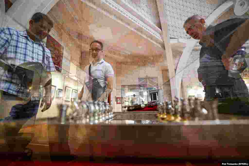 Museum visitors look at a chess set made of gold and silver.