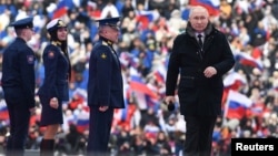 Russian President Vladimir Putin (right) attends a concert dedicated to Russian soldiers involved in the military campaign in Ukraine on the eve of Defender of the Fatherland Day at Luzhniki Stadium in Moscow on February 22.