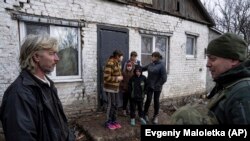 A Fehér Angyalok ukrán rendőrtisztje próbál rábeszélni egy családot, hogy evakuáljon biztonságos területre az ukrajnai Krasznohorivkából 2023. február 21-én. A hatóságok hónapok óta arra kérik a kelet-ukrajnai harcok közelében lévő területeken élő civileket, hogy távozzanak