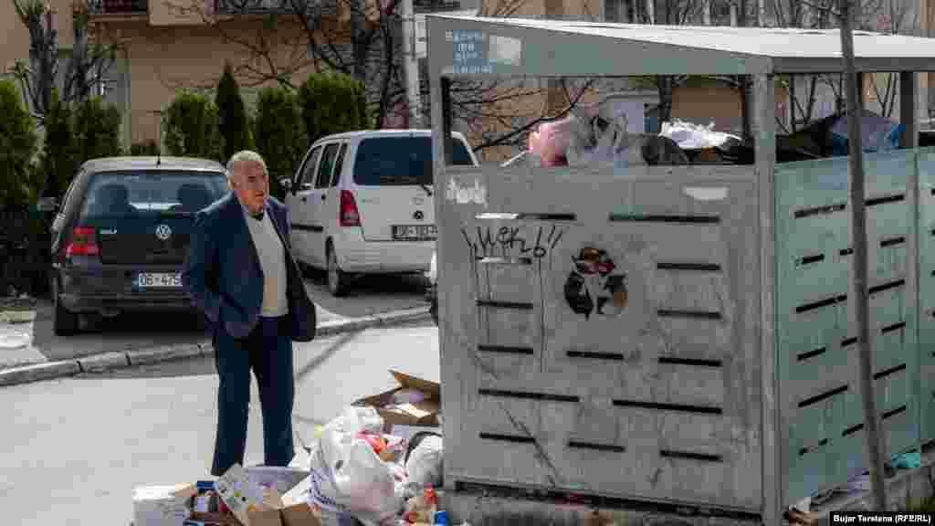 Një qytetar shikon kontejnerët e stërmbushur me bërllok.