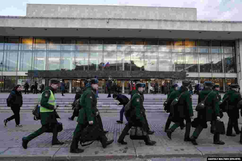 Military cadets walk in front of the concert hall. The heightened security measures will likely continue in crowded areas, on transportation, and at airports nationwide during the coming weeks.