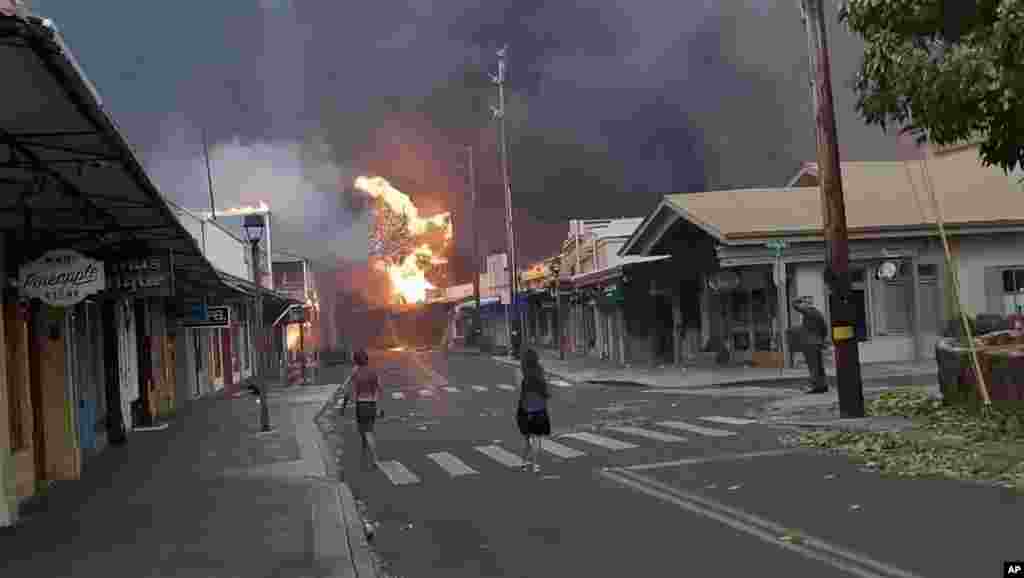 Луѓето гледаат како чад и пламен го исполнуваат воздухот на улицата Фронт во центарот на Лахаина, Мауи, вторник, 8 август 2023 година. Официјалните лица на Мауи соопштија дека шумскиот пожар во историскиот град изгорел делови од една од најпопуларните туристички области на Хаваи.