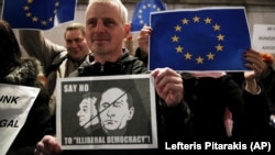 Плакат с изображениями премьер-министра Венгрии Виктора Орбана (слева) и президента России Владимира Путина во время акции протеста представителей венгерской диаспоры в Великобритании. Лондон, 17 ноября 2014 года