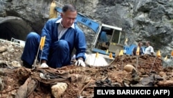 A forensics expert collects human remains at a mass grave in Miljevine, near the eastern Bosnian town of Foca, in 2004.