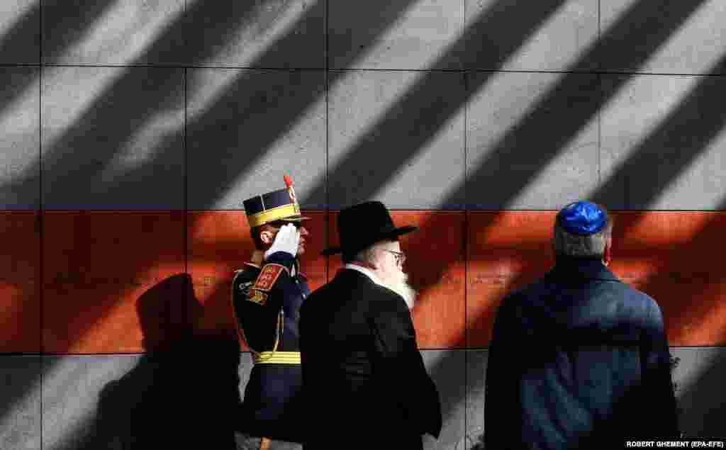 A Romanian honor guard soldier salutes as First Rabbi of Romania Rafael Shaffer (center) pays his respects at a ceremony marking the Romanian National Day of Commemorating the Holocaust at the Holocaust Memorial in Bucharest.