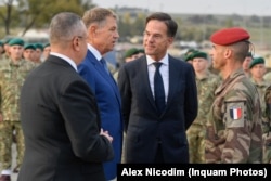 Premierul olandez Mark Rutte (al doilea la dreapta), președintele României Klaus Iohannis (al doilea la stânga) și președintele Partidului Național Liberal, Nicolae Ciuca (stânga), pe atunci premier, vizitează baza militară de la Cincu, din Brașov, România, în octombrie 2022.