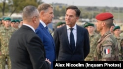 Premierul olandez Mark Rutte (centru) și președintele român Klaus Iohannis (centru-stânga) în timpul unei vizite la baza militară de la Cincu, în Brașov, pe 12 octombrie 2022.
