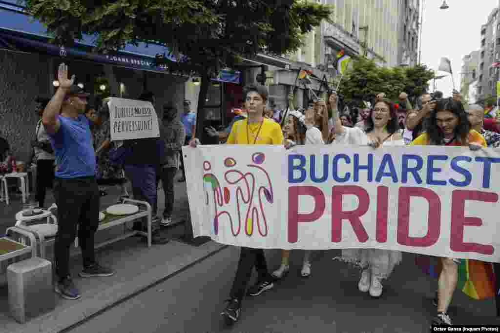 Participanții la parada Bucharest Pride 2023 trec pe lângă o persoană care poartă o pancartă cu mesajul &bdquo;Iubirea nu este perversiune&rdquo;.