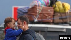 ARMENIA - A refugee from Nagorno-Karabakh holds a child while standing next to a car upon their arrival in the border village of Kornidzor, September 26, 2023.