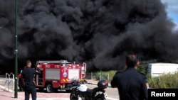 Израелски полицаец стои веднаш до чадот од пожарот по дојдовните ракети од Либан кон Израел во Безет, северен Израел, 6 април 2023 година.