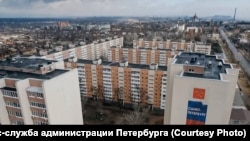 В России пропаганда активно призывает вкладываться в жилье на оккупированных территориях Украины. На фото – новостройки на фоне разрушенного Мариуполя, 2023 год