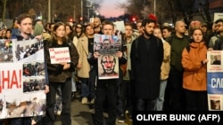 A protester (center) holds images depicting Aleksei Navalny and Russian President Vladimir Putin at demonstration outside the Russian Embassy in Belgrade on February 16, following the news of Navalny's death at an Arctic prison.