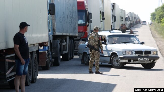 Камиони чакат да преминат контролно-пропускателния пункт Армянск между област Херсон и Крим на 23 юни. Снимката е направена един ден след като мостът Чонгар беше повреден при ракетен удар и затворен за движение.