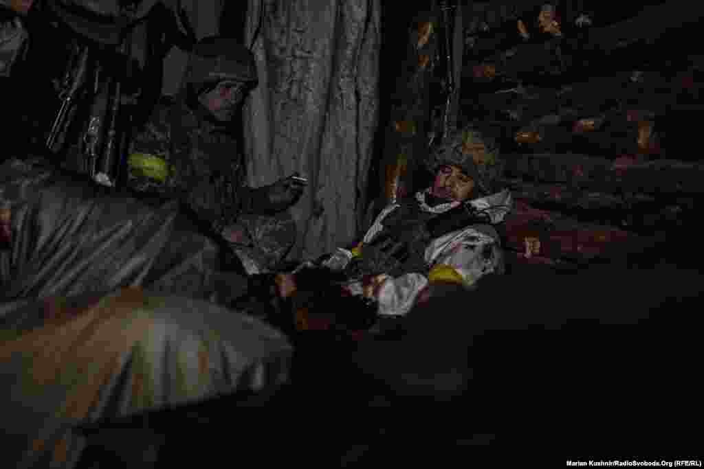 With space inside their dugout at a premium, the soldiers must take turns sleeping while others sit and wait in the darkness.