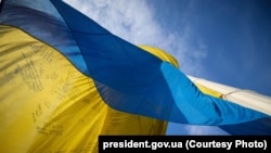 У Києві підняли прапор України з «особливими словами й підписами», залишеними українськими захисниками та захисницями
