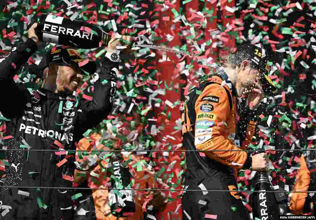 Winner Oscar Piastri (right) of McLaren is sprayed with champagne by third-placed Mercedes driver Lewis Hamilton on the podium after the Formula One Hungarian Grand Prix at the Hungaroring race track in Mogyorod near Budapest on July 21.