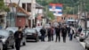 Njerëz duke ecur në një rrugë, sipër së cilës qëndrojnë flamuj të Serbisë, në Zubin Potok, Kosovë, më 31 maj 2023.