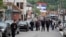 Njerëz duke ecur në një rrugë, sipër së cilës qëndrojnë flamuj të Serbisë, në Zubin Potok, Kosovë, më 31 maj 2023.
