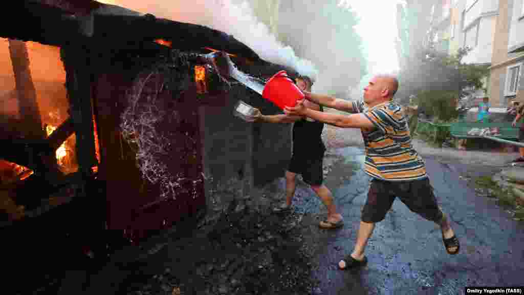 Мужчины пытаются потушить пожар, вспыхнувший после удара по удерживаемому Россией селу Лидиевка в Донецкой области, 31 августа. Киев заявил, что продвигается медленно, чтобы минимизировать потери