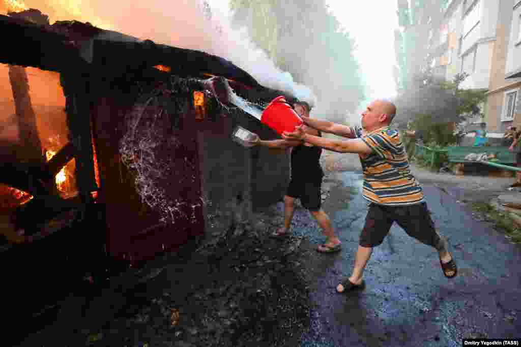 A man attempts to douse a fire with water after a strike on the Russian-held village of Lidiyevka in the Donetsk region on August 31.&nbsp; Kyiv has said it is advancing slowly to minimize losses.&nbsp;