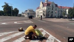 Мужчина прикрывает тело погибшего человека после российской атаки на Чернигов, 19 августа 2023 года