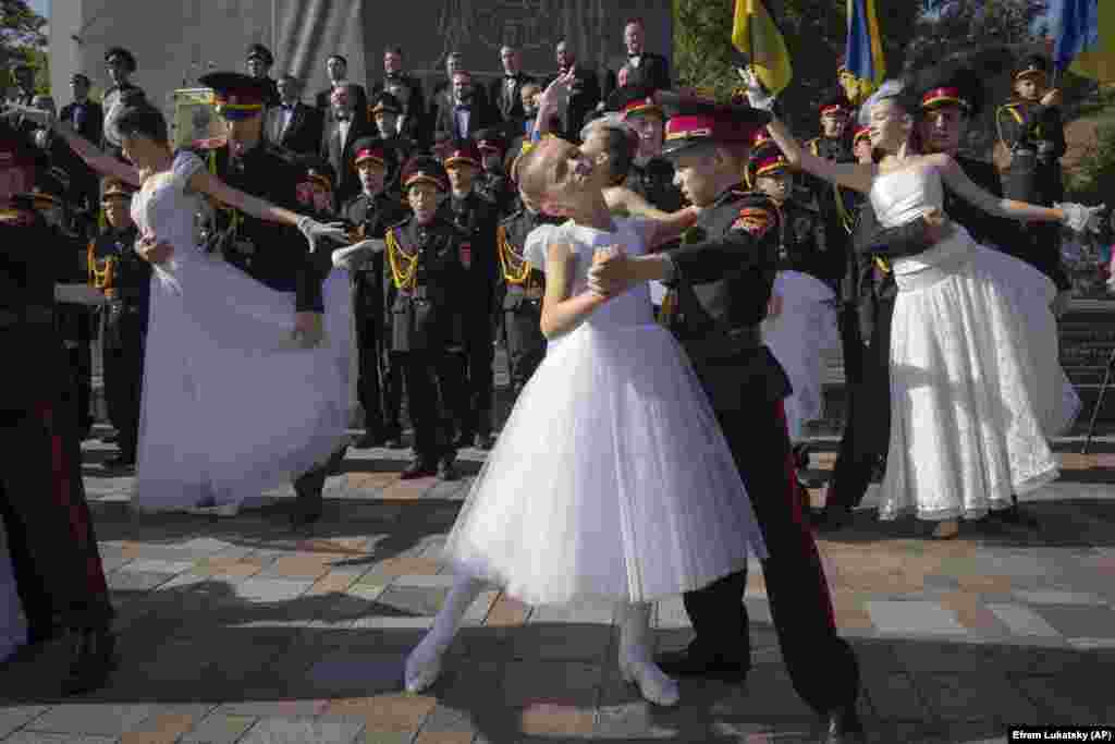 Djem të rinj të veshur si kadetë dhe nxënëse shihen duke vallëzuar gjatë një ceremonie betimi në një monument të princit legjendar Volodymyr, një nga simbolet e kryeqytetit ukrainas në Kiev.