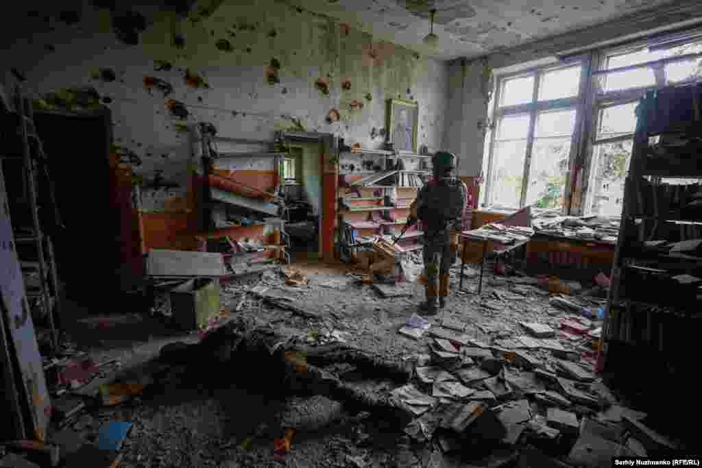 A Ukrainian serviceman stands near the body of a Russian soldier who was killed during the storming of the village.