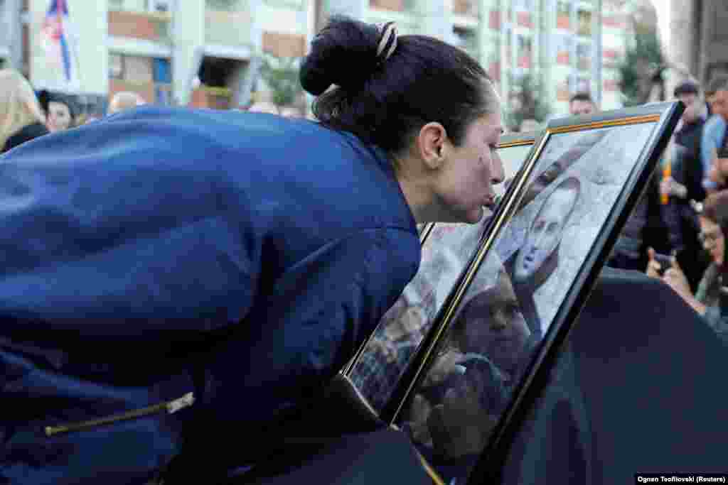 A woman kisses a photograph as Kosovo Serbs hold a vigil in the northern city of Mitrovica for those killed in a monastery siege after gunmen in armored vehicles stormed a village in an ethnic Serbian-majority region.