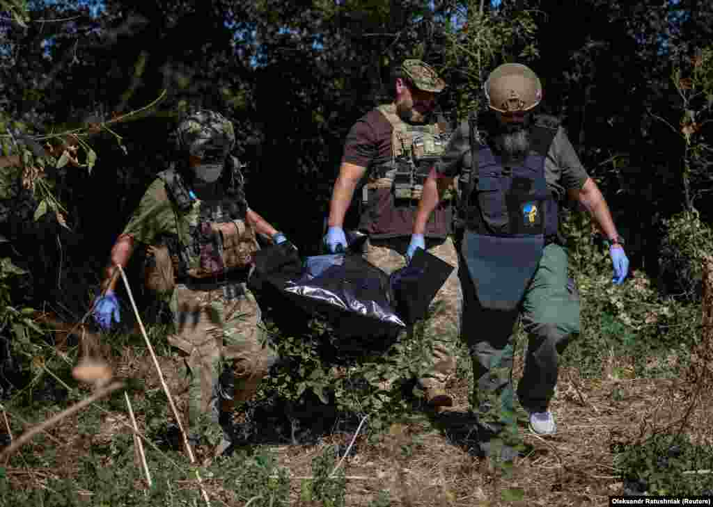 Voluntari ucraineni colectând cadavrul unui soldat rus mort în satul Blahodatne, în sud-estul Ucrainei, pe 8 septembrie. La trei luni de la bătălia pentru eliberarea satului, zona a fost considerată suficient de sigură pentru ca voluntarii să înceapă sarcina macabră de a recupera cadavrele. Drumul care duce în sat a fost supranumit &bdquo;drumul morții&rdquo; din cauza numărului de soldați ruși uciși. &nbsp;