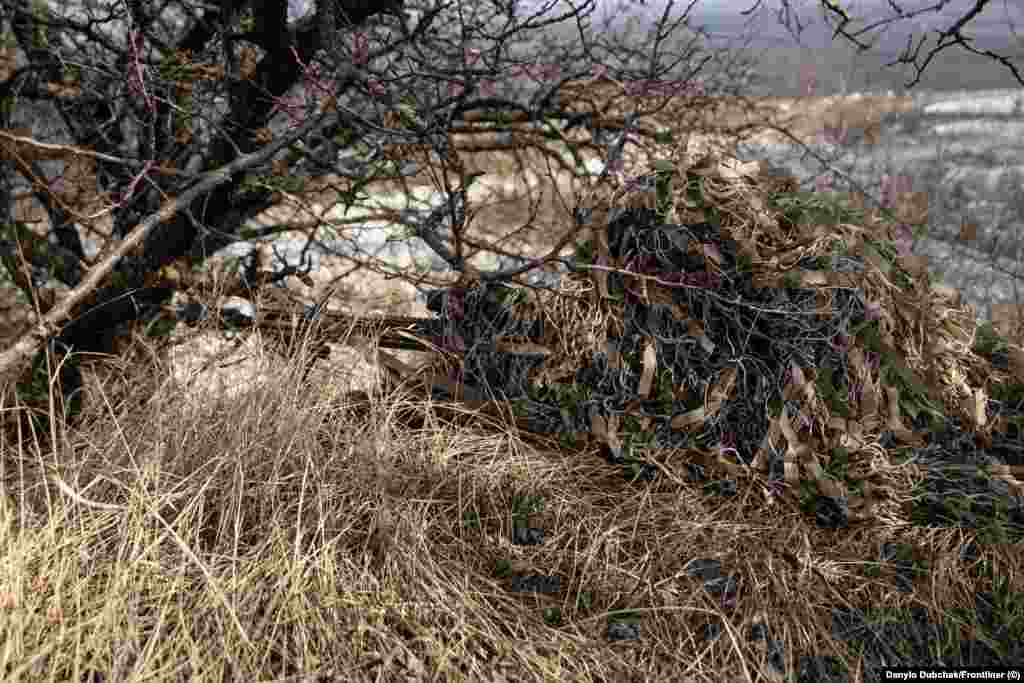 A soldier dressed in a camouflage cloak aims his rifle during the training. The snipers are draped in camouflage known in English as ghillie suits. In Ukrainian and Russian, the coverings are called &ldquo;kikimora,&rdquo; after a witchy spirit of Slavic folklore. &nbsp;