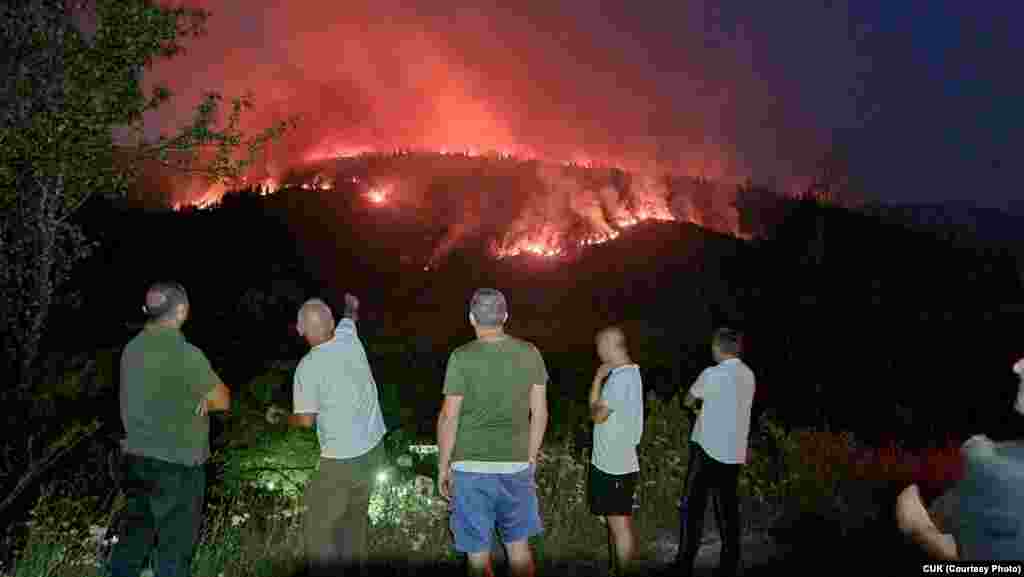 Residents watch the progress of a wildfire near the village of Vrben in North Macedonia.&nbsp;