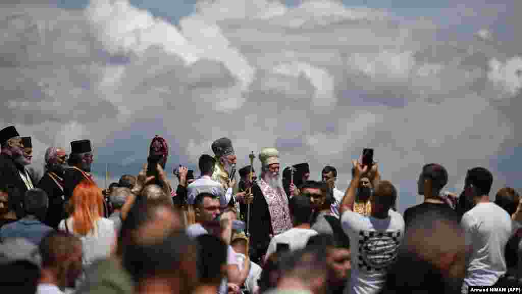 Ljudi svojim telefonima slikaju verske vođe koji posvećuju himne i pesme svetom Vidu i mučenicima bitke.