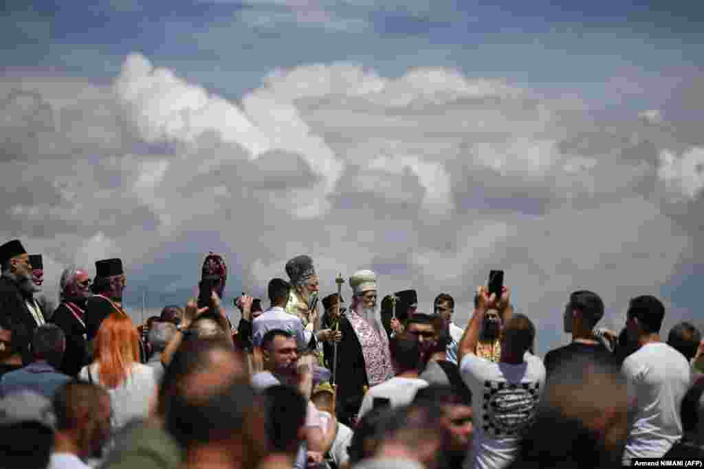 People take pictures with their phones of the religious leaders who dedicate hymns and chants to St. Vitus and the martyrs of the battle.