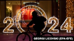 Një burrë duke ngarë biçikletën ndërsa kalon pranë zbukurimeve të vendosura për Vitin e Ri në Shkup.