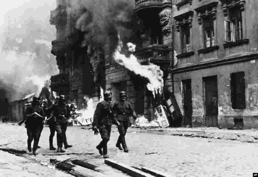 Nijemci su nakon gušenja ustanka 16. maja 1943. godine digli u vazduh sinagogu u znak odmazde. - na fotografiji: nacistički oficiri šetaju ulicama likvidiranog Varšavskog geta, proljeće 1943. godine.
