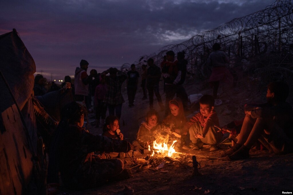 Fëmijët emigrantë, në mesin e tyre edhe Vallolet, 4 vjeç nga Peruja, ulen rreth një zjarri pranë bregut të lumit Rio Grande derisa janë duke pritur me familjet e tyre për më shumë se dy ditë për t'u dorëzuar tek autoritetet e imigracionit më 23 mars. 