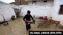 A boy rescues belongings from a flooded home after heavy rains in Peshawar, Pakistan, in April.