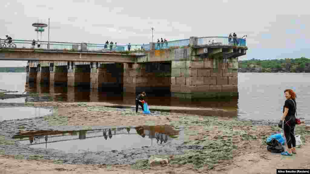 Zaporizzsjaiak a város egyik strandját tisztítják június 10-én, az árvíz visszahúzódása után.&nbsp;Az árvizek lépfenével fertőzöttek is lehetnek